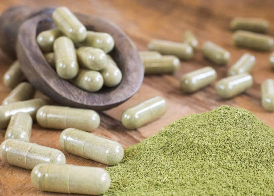 Kratom capsules and powder on a table from Golden Road Botanicals